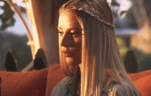 a woman with long blonde hair is sitting on a couch .