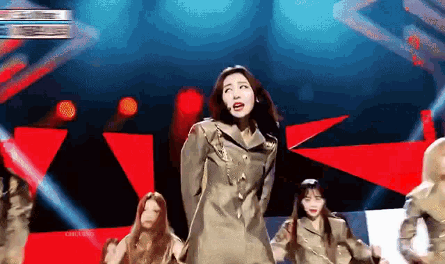 a group of women are dancing on a stage in front of a blue background .