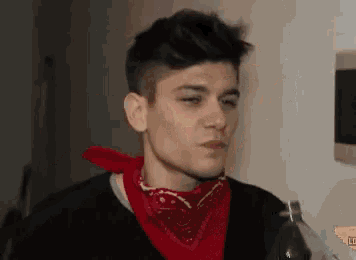 a man wearing a red bandana and holding a bottle of soda .