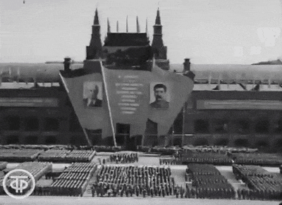 a black and white photo of a parade in front of a large building
