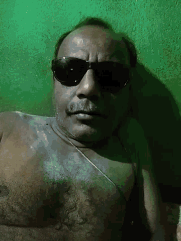 a man wearing sunglasses and a necklace is laying down