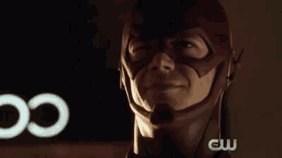 a close up of a man in a flash costume with a cw logo in the background