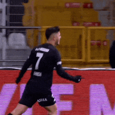 a soccer player wearing a number 7 jersey is celebrating a goal on a soccer field .