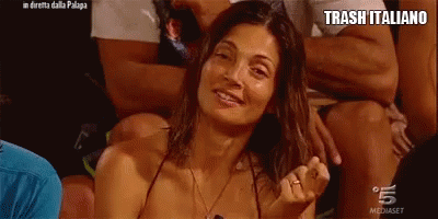 a woman in a bikini is sitting in a crowd with the words trash italiano written on the bottom .