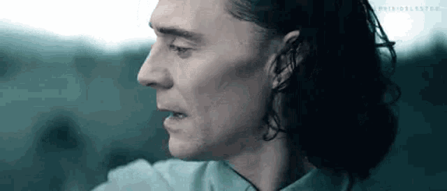 a close up of a man 's face with long hair in a dark room .
