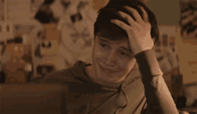 a young man is sitting at a desk holding his head .