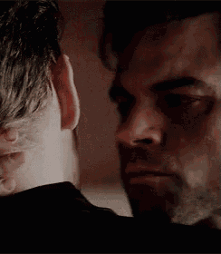 a man is touching another man 's neck in a close up .