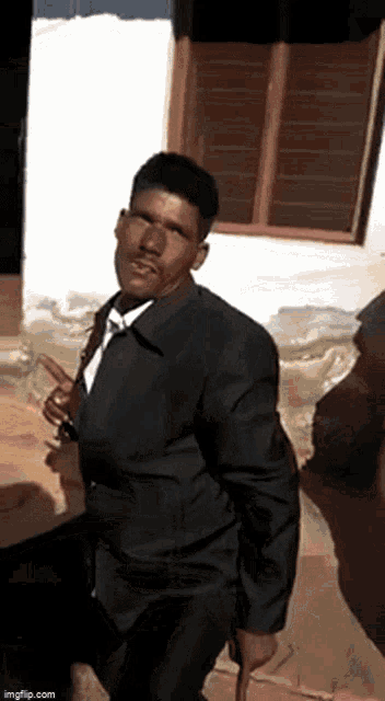 a man in a suit is standing in front of a window