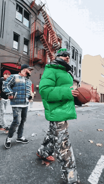 a man in a green jacket is carrying a basketball