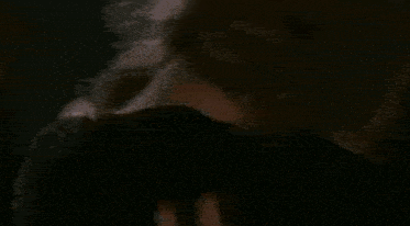 a man and a woman are kissing in front of a crowd in a dark room .
