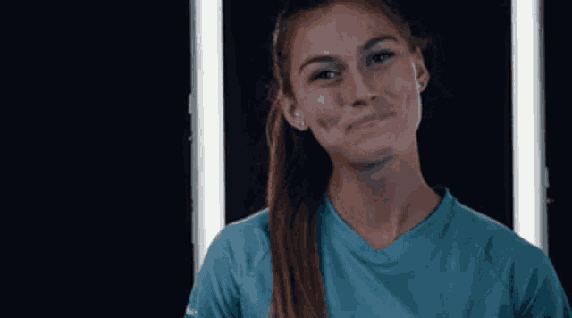 a woman in a blue shirt is smiling in front of two lights