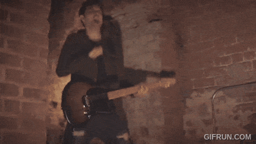 a woman singing into a microphone while a man plays a guitar in the background
