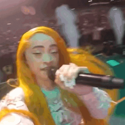 a woman with yellow hair is singing into a microphone .