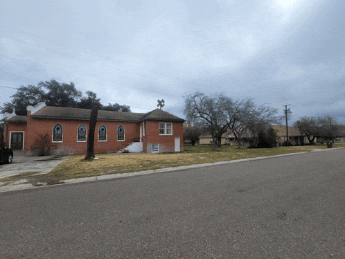 a church with stained glass windows sits on the side of a road