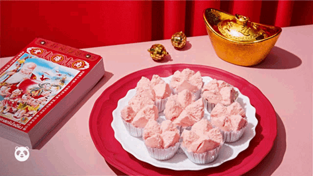 a plate of pink cupcakes sits on a table next to a stack of chinese calendars