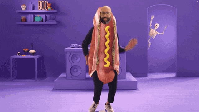 a man in a hot dog costume is dancing in a purple room