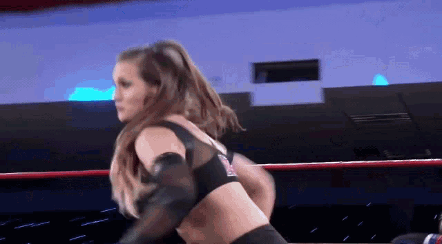 a woman is standing in a wrestling ring with a man .