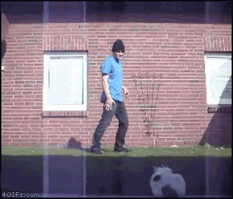 a man in a blue shirt and black hat is walking in front of a brick building