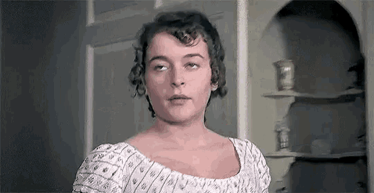 a woman in a white dress is standing in front of a window .