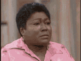 a woman in a pink jacket is crying while sitting down .