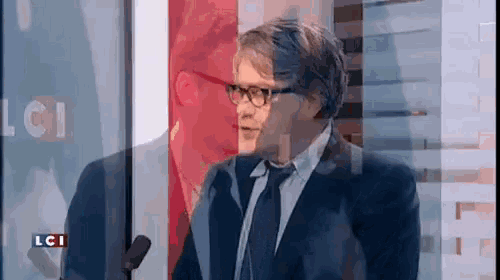 a man in a suit and tie is talking into a microphone on lci
