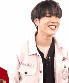 a young man wearing a pink jacket is laughing and looking up .