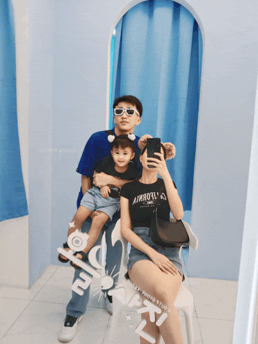 a family taking a picture in front of a mirror with the words happy photo studio on the bottom right corner