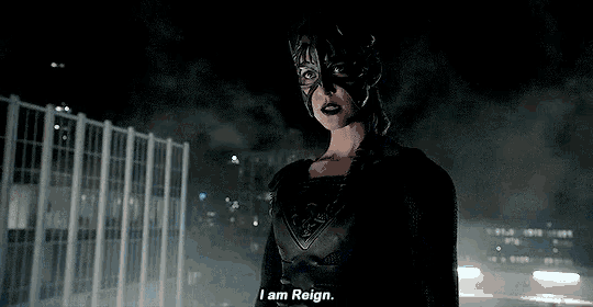 a woman in a black costume is standing in front of a building at night .