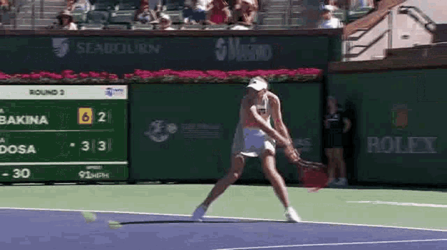 a woman is playing tennis on a court with a rolex sign in the background