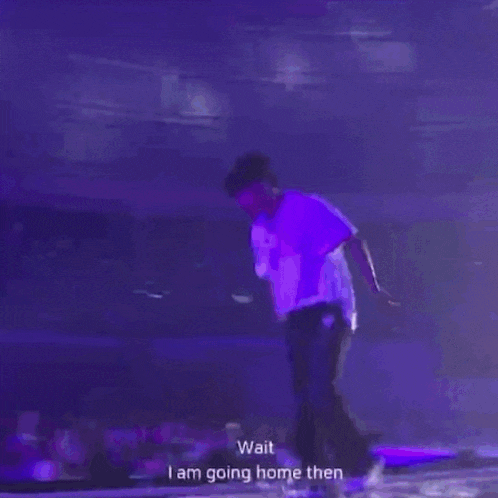 a man in a purple shirt is dancing on a stage with the words `` wait i am going home then '' .