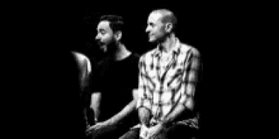 two men are sitting next to each other in a dark room laughing .