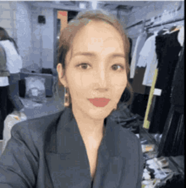 a woman in a suit is taking a selfie in a room with clothes .