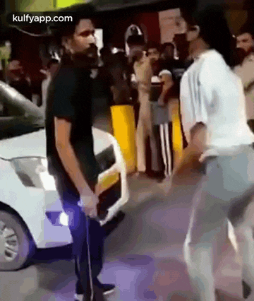 a man is standing next to a woman in front of a car .