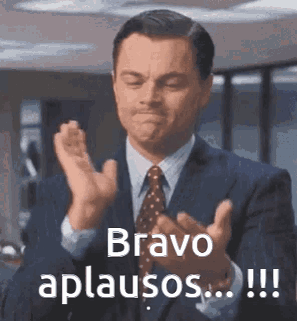a man in a suit and tie is clapping his hands with the words bravo aplausos !!! above him