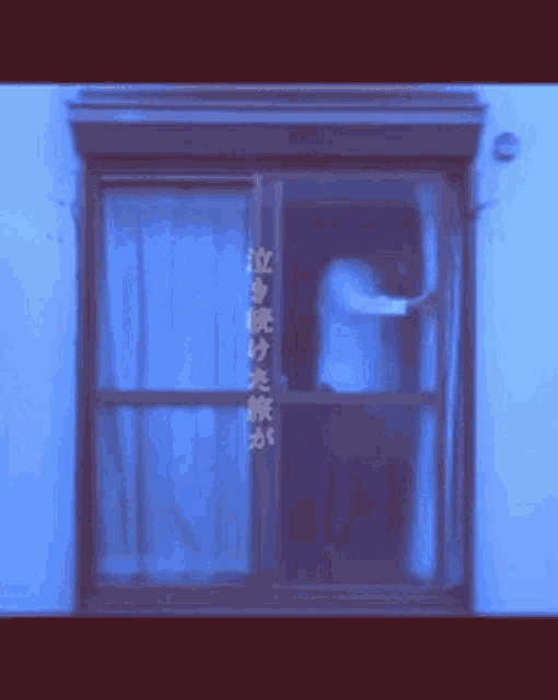 a man is standing in a window with chinese writing on the wall behind him