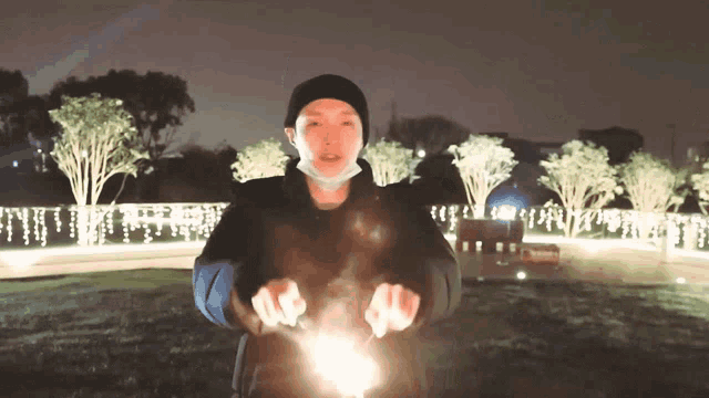 a man wearing a mask is holding a sparkler in front of him