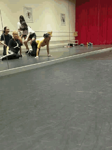 a group of people are dancing in a room with a red curtain behind them