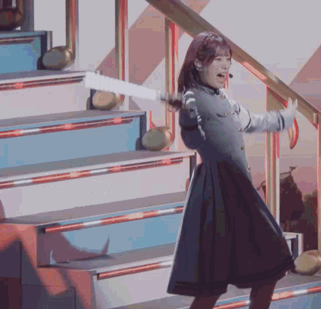 a girl in a blue dress is standing on a set of stairs