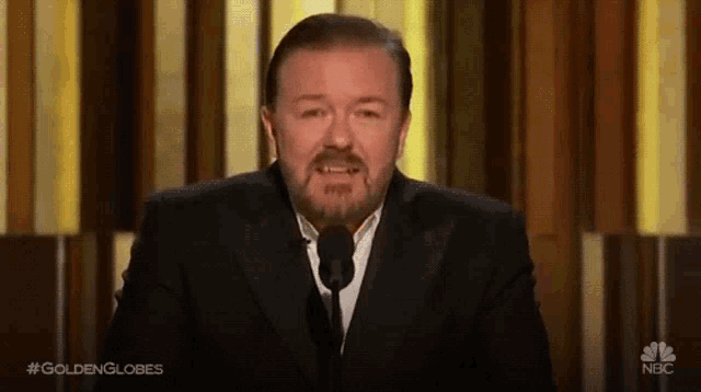 a man in a suit is speaking into a microphone with the hashtag goldenglobes