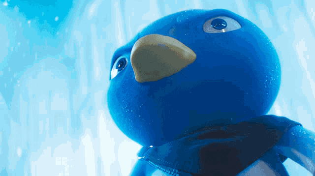 a blue stuffed animal with a scarf around its neck looks at the camera