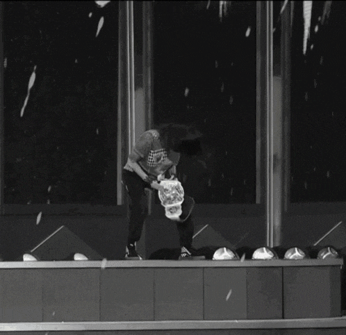 a black and white photo of a woman standing on a stage holding a bag that says ' coca cola ' on it