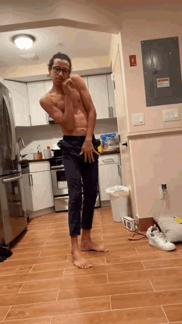 a shirtless man standing in a kitchen with a bag of chips