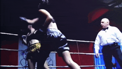 two women are fighting in a boxing ring and one of them is wearing a black bra .