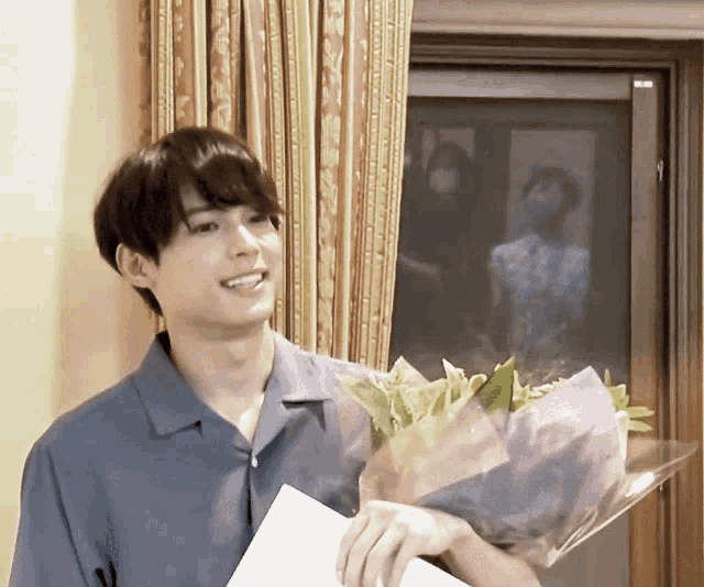 a man in a blue shirt holds a bouquet of flowers