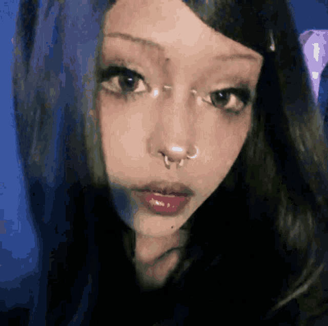 a close up of a woman 's face with a nose piercing