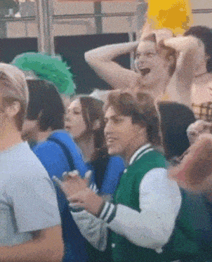 a man in a green jacket is standing in a crowd