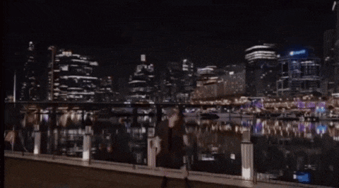 a person is walking on a bridge at night with a city skyline in the background