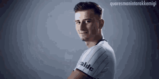 a man in a striped shirt with the word valde on the sleeve is smiling .