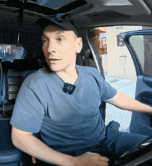 a man wearing a hat and a blue shirt is sitting in a car