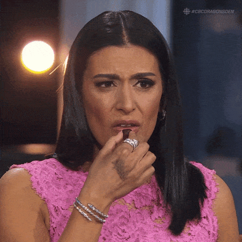 a woman in a pink lace dress eating a chocolate bar